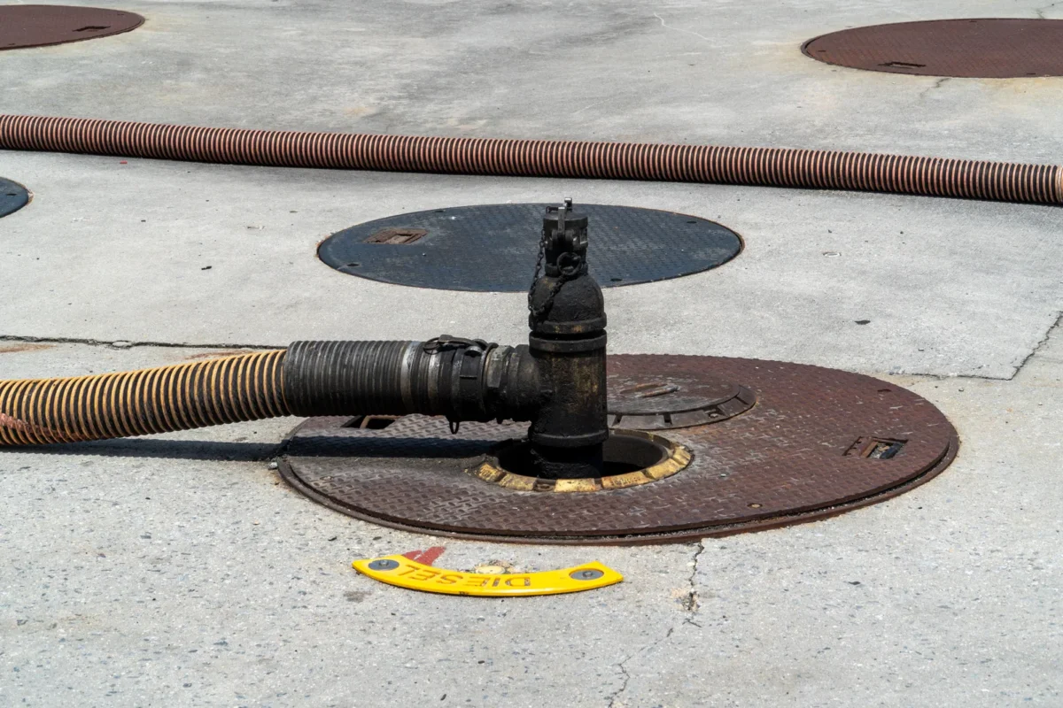 Fuel transfer hose connected to an underground tank filling point.