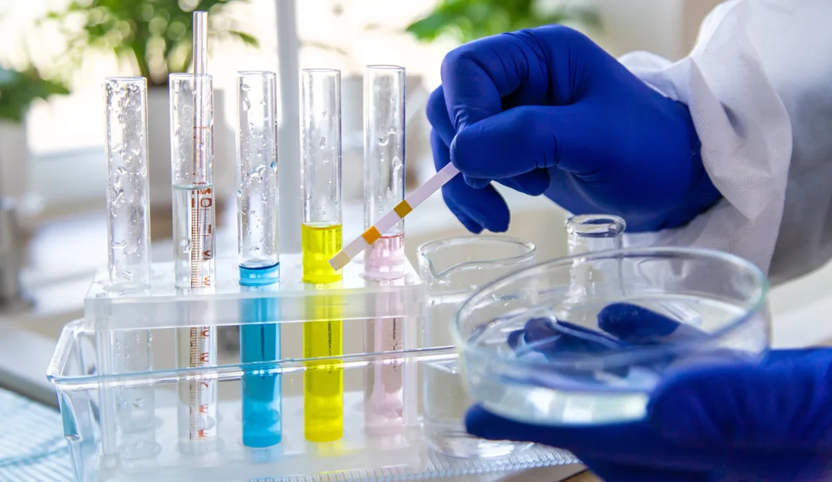 Laboratory technician testing a water sample using glass laboratory equipment.