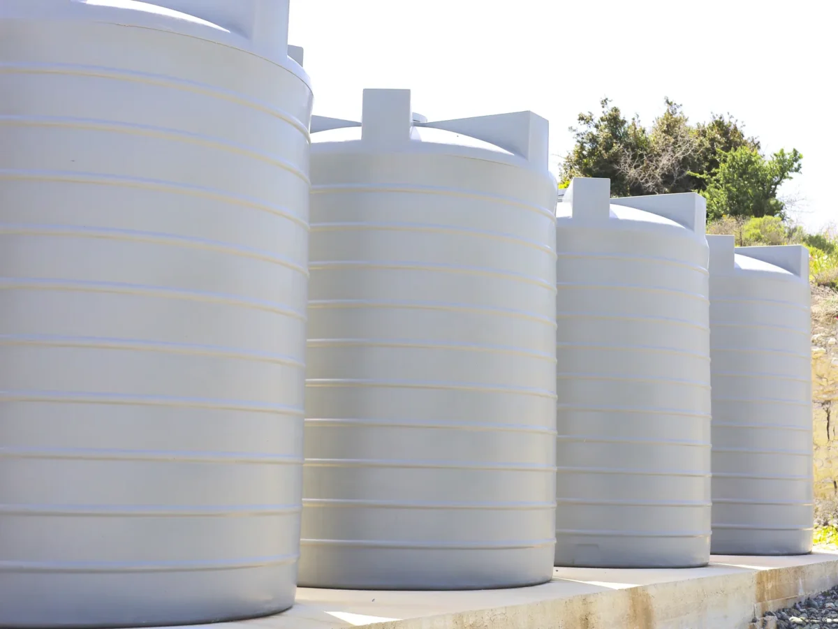 White water storage tanks arranged on an outdoor concrete base.