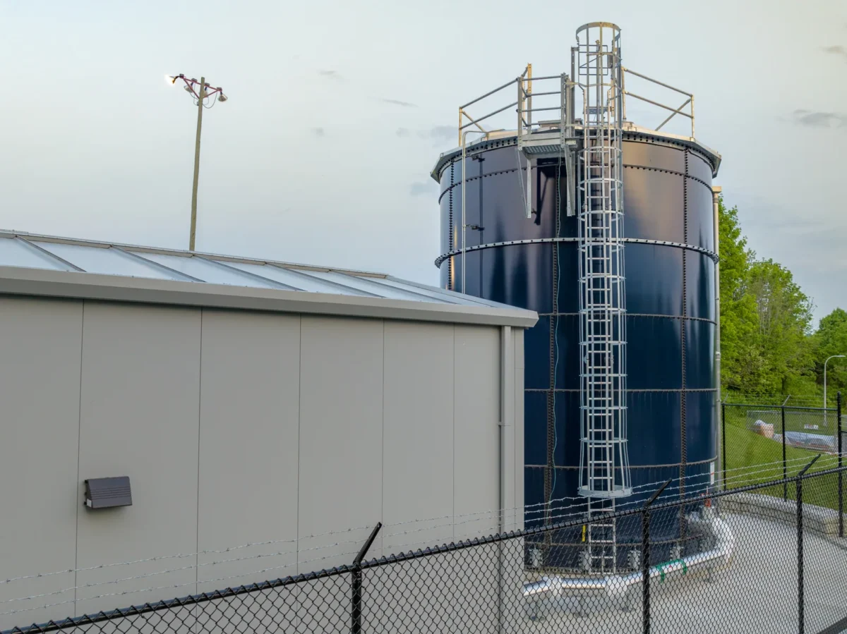 Large blue water storage tank beside a commercial building.