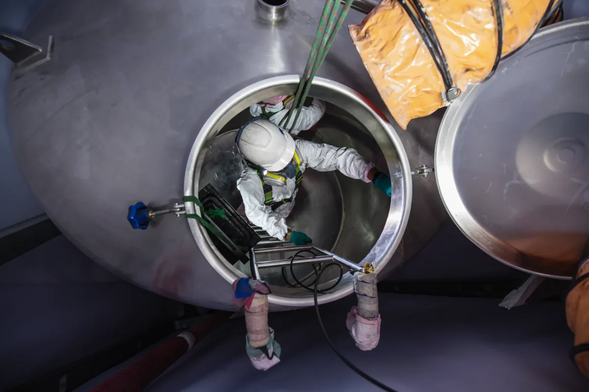 Confined-space tank access with ropes and ventilation equipment.